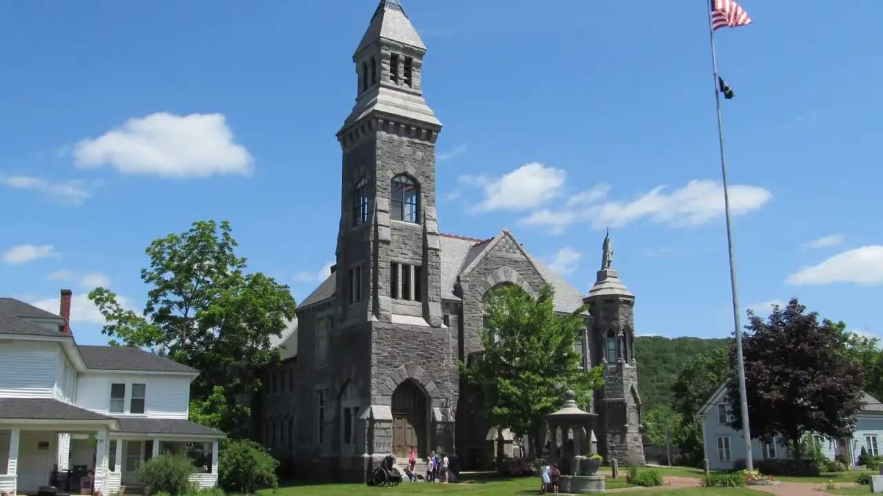 Granite Richardsonian Romanesque Memorial Hall with a corner tower and American flag, Monson, Massachusetts